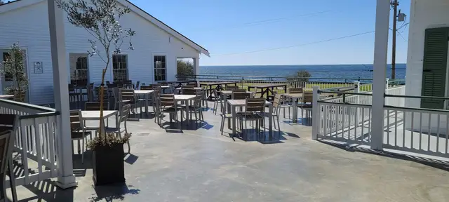 Tables on the second-story deck with the Lake Pontchartrain horizon behind