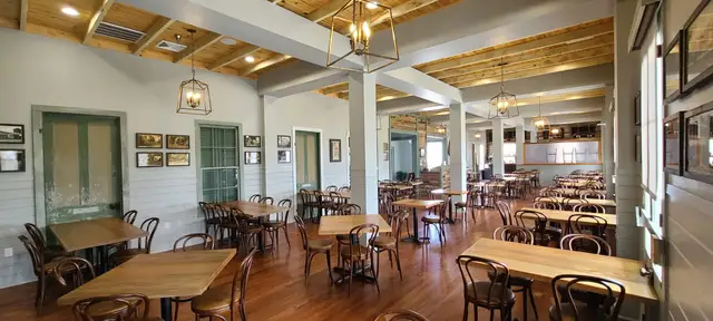 The Frapart dining room with wood floors, bentwood chairs and framed postcards on beadboard walls
