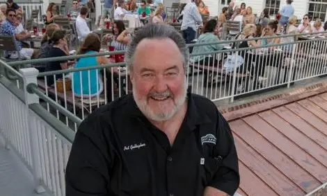 Pat Gallagher smiling on the deck with diners behind him